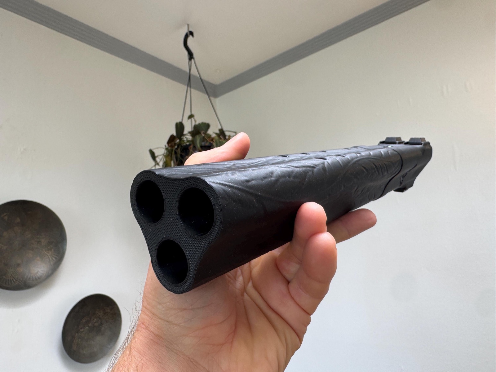 Looking into the foot end of the black Raven triple drone flute, held in one hand, showing its three bores