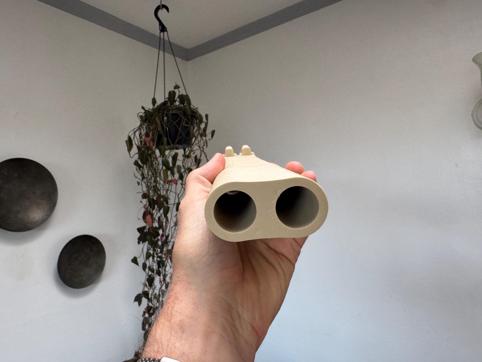 Foot of the Desert Rose drone flute held in one hand, showing the two round bores of its twin chambers