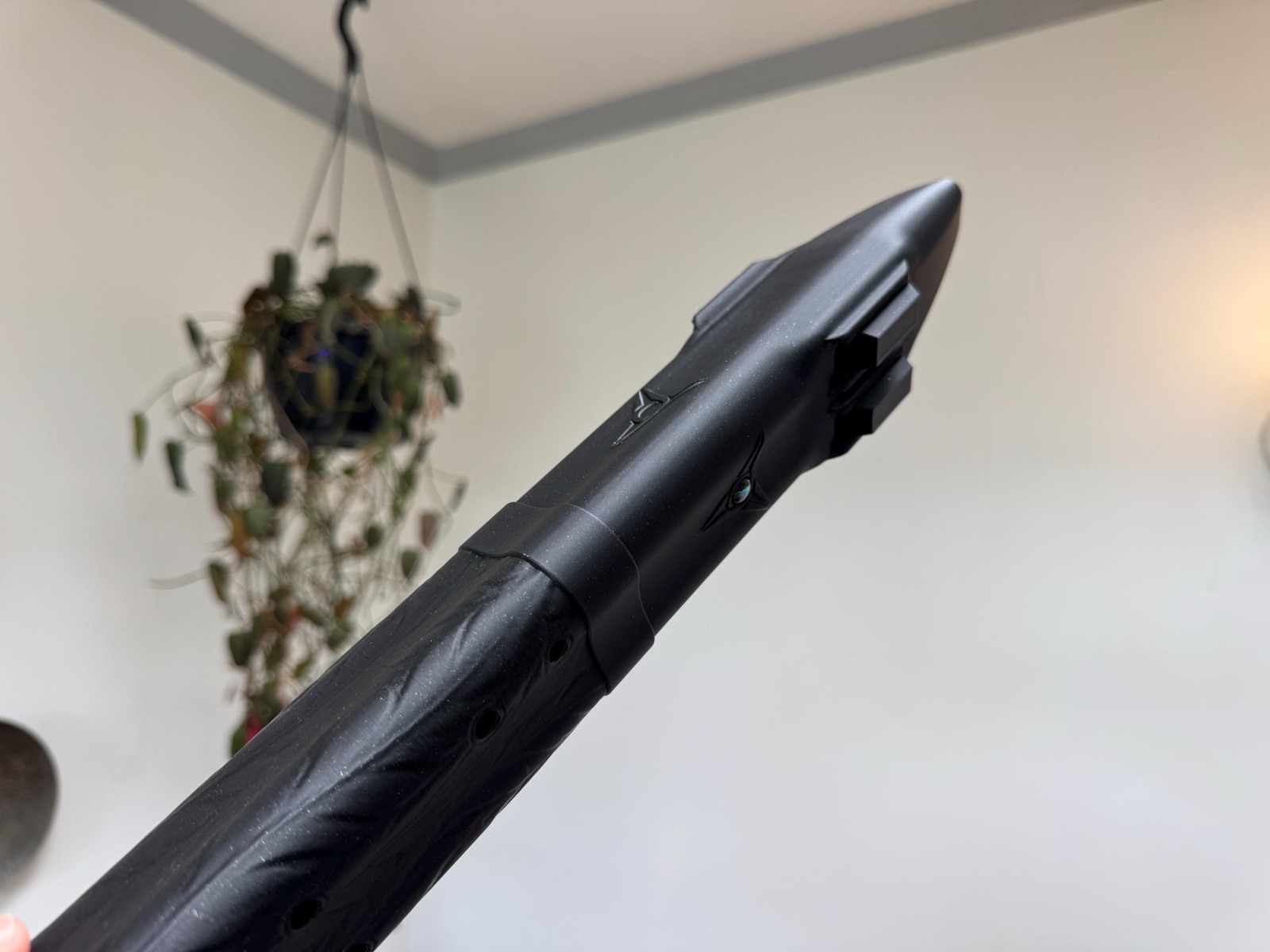 Close view of the tapered beak-shaped head of the Raven flute with the mother-of-pearl inlay and drone blocks